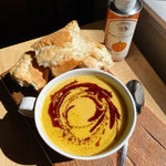 A delicious bowl of butternut squash soup sitting next to a can of La Tourangelle pumpkin seed oil.