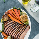 Brisket on plate with carrots and other vegetables.