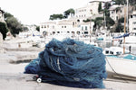 a large fishnet piled up on a dock in a fishing village