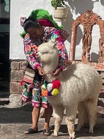 Peruvian woman placing a decorative neckband over a lama